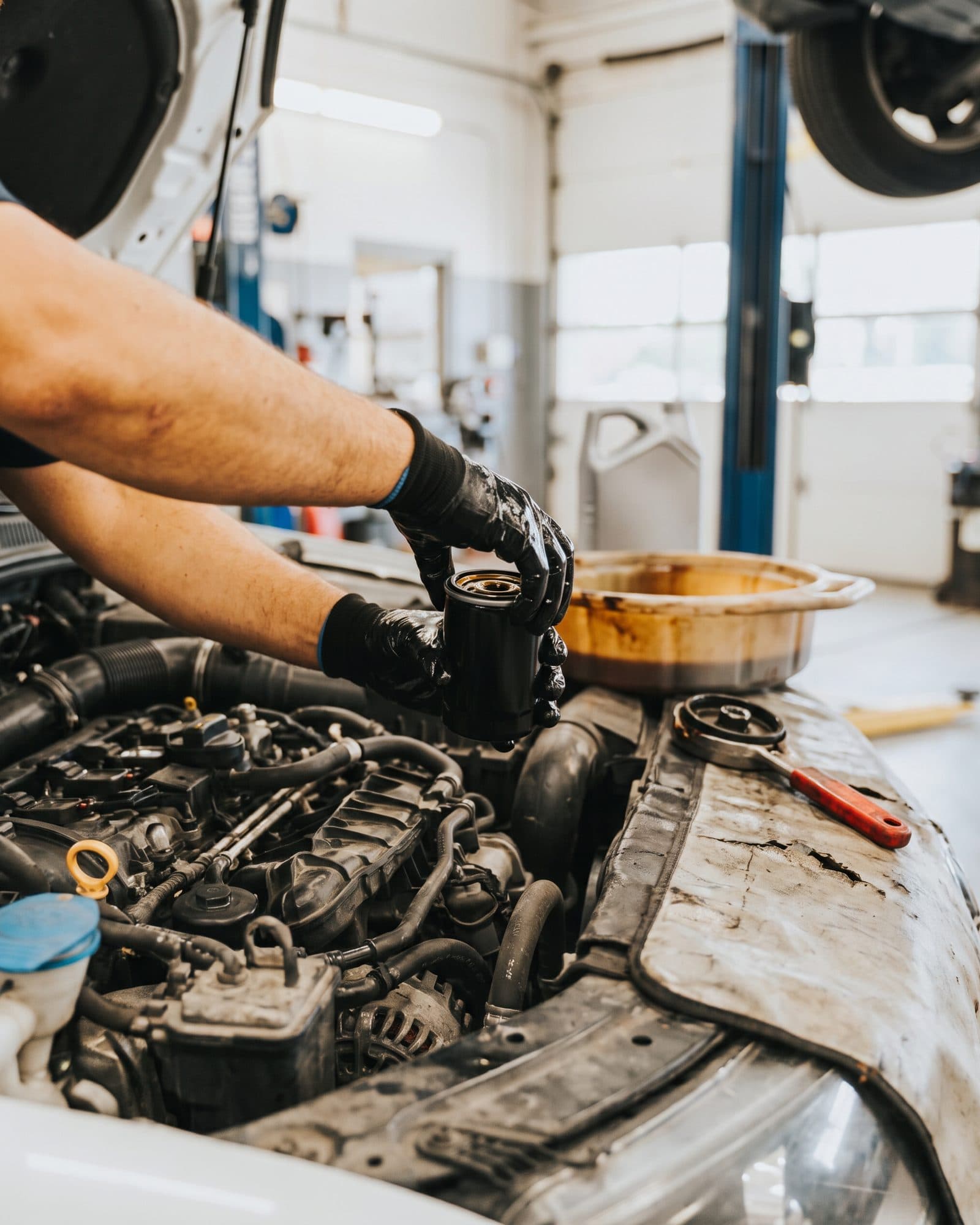 Gloved hands fitting a new oil filter under the hood during an oil change in Etobicoke